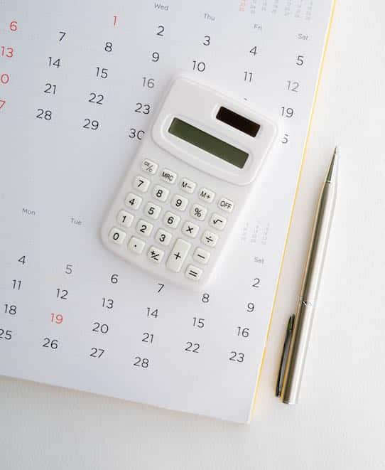 close up top view on calculator with calendar and pen on white background with copy space for business and financial activity monthly concept