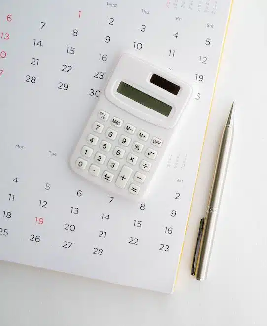 close up top view on calculator with calendar and pen on white background with copy space for business and financial activity monthly concept